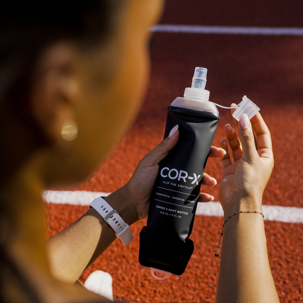 Otváranie silikónového náustka čiernej COR-X soft flask Series 2 na atletickej dráhe