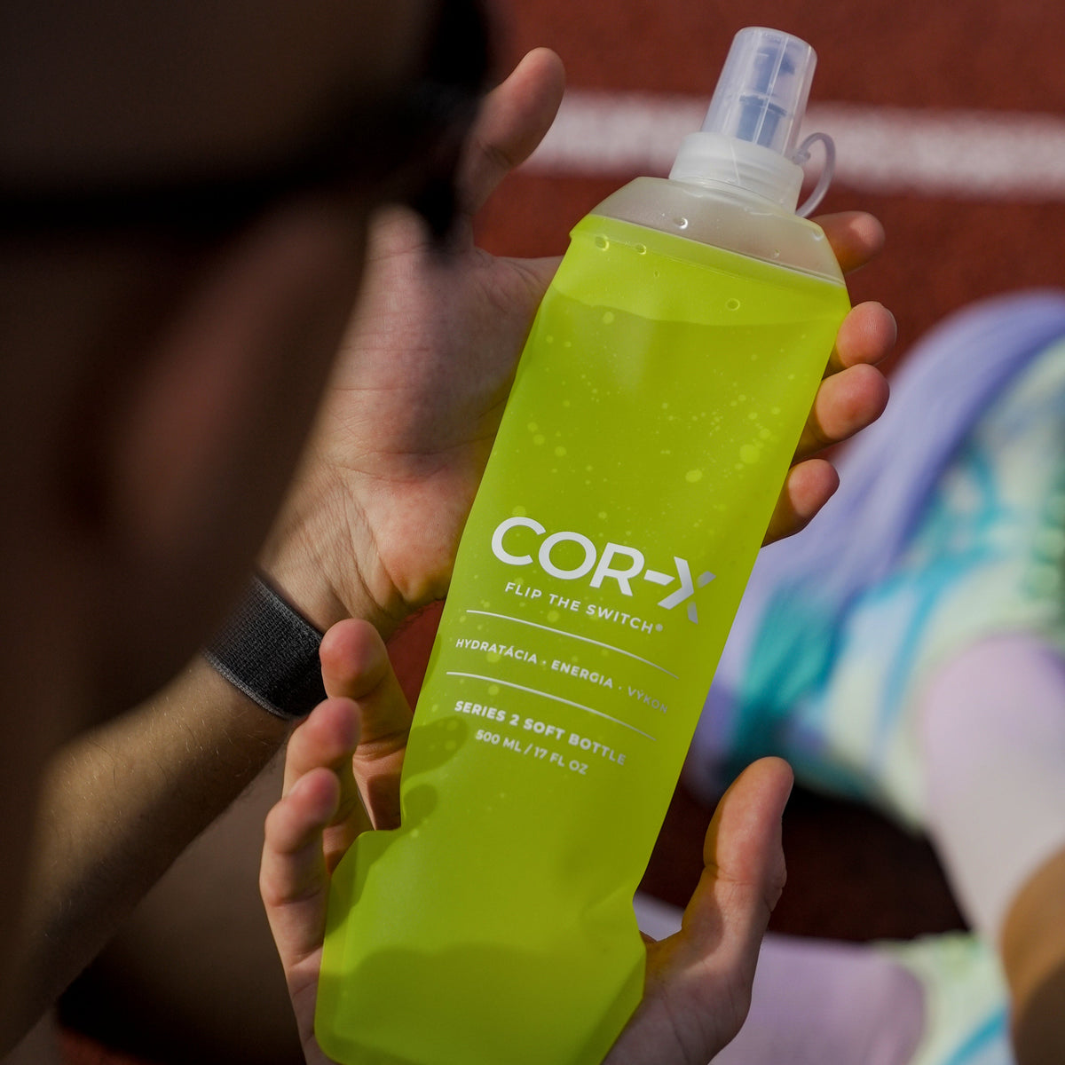 Limetková COR-X soft flask Series 2 držaná v ruke počas prestávky na atletickej dráhe